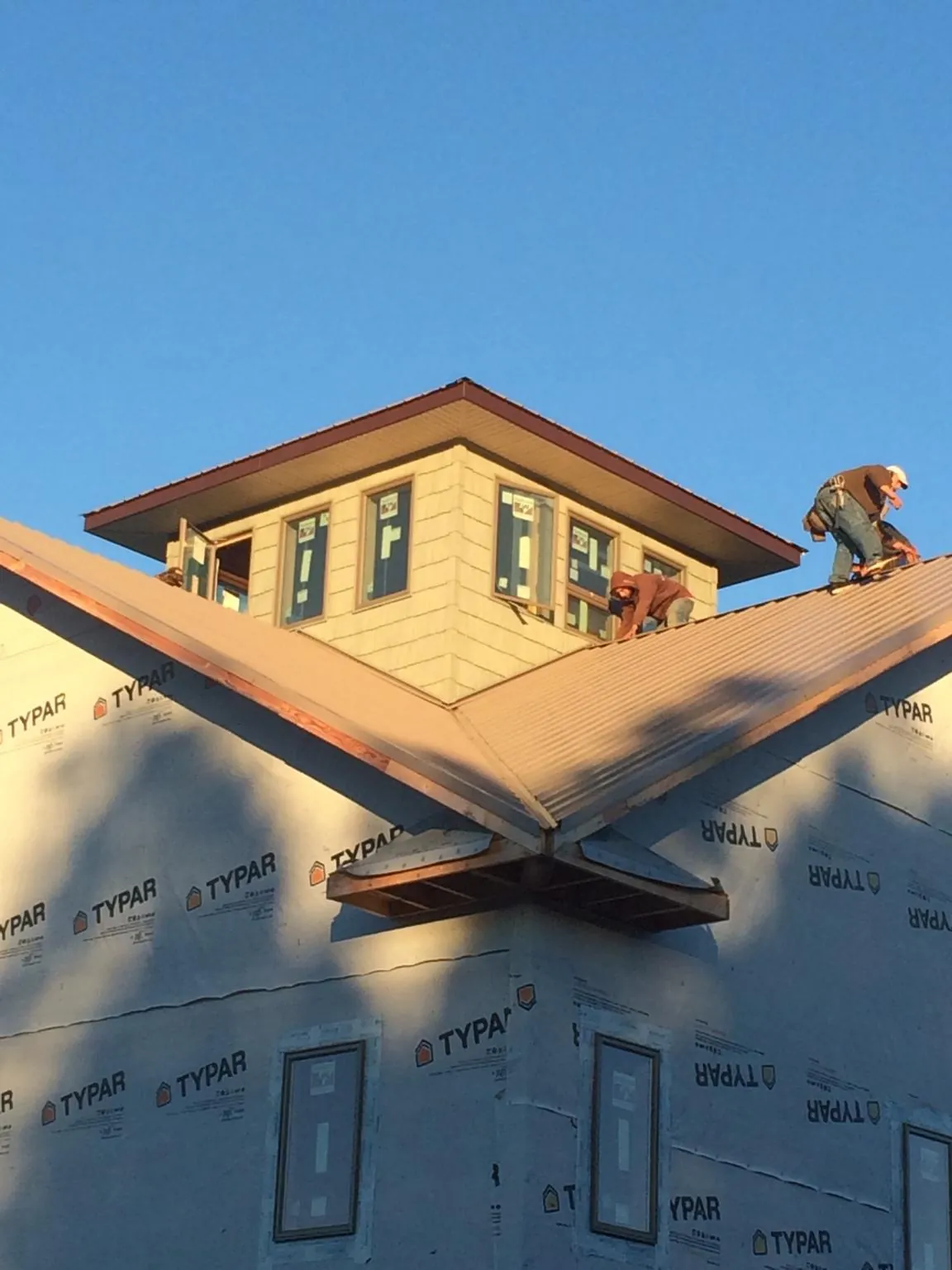 Roofers working around a rooftop cupola on a new metal roof at sunset — Roof Waterproofing in Shepherd by Roofing Brothers